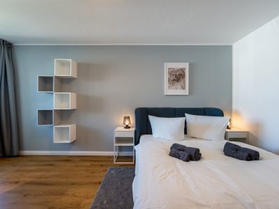 Modernes Schlafzimmer mit Doppelbett, Nachttischen und heller Wandgestaltung