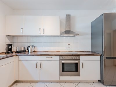 Moderne Einbauküche mit weißen Schränken, Ceranfeld und Edelstahl-Dunstabzug