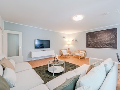 Wohnzimmer mit Fernseher, Sofa und dezentem Licht – stilvoll eingerichtet